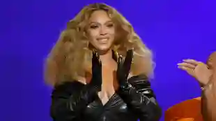 Beyoncé claps her hands, which she's wearing black gloves on