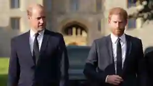 Prince William and Prince Harry walk side by side in black suits in September 2022