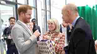 Prince Harry accepting a baby gift at the Youth Zone from Lady Jane Woodward, a long-time family friend.