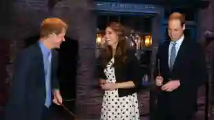 El príncipe Harry, Catalina, y el príncipe William se ríen mientras sostienen varitas usadas en el set del callejón "Diagon" en la serie de 'Harry Potter' en abril 26, 2013 en Londres, Inglaterra.