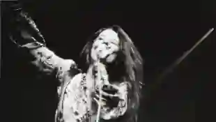 Janis Joplin on stage at New York City's Madison Square Garden, holding a microphone in one hand the