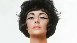 Actor Elizabeth Taylor in a studio, wearing a costume intended to evoke her role in the movie Cleopa