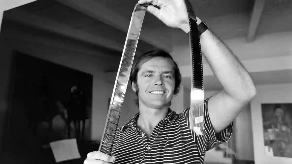 American  film  actor  Jack  Nicholson  grims  as  he  holds  up  a  strip  of  film  negative  in