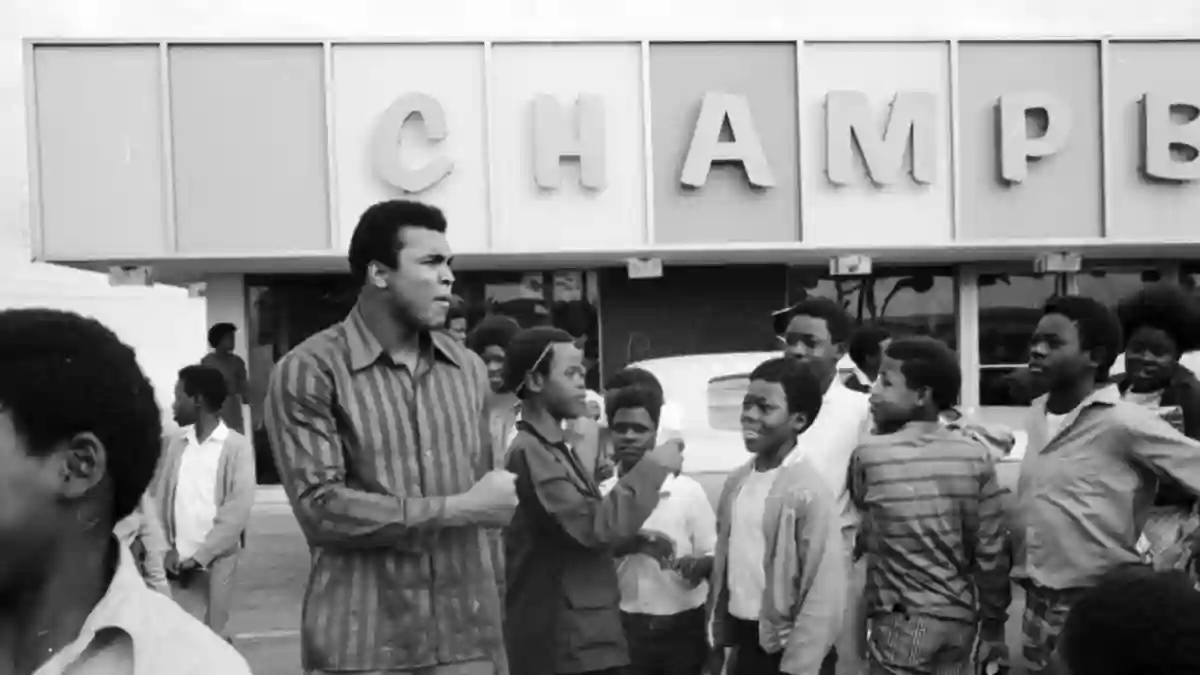 Professional  boxer  Muhammad  Ali  standing  with  a  group  of  children  near  a  grocery  store