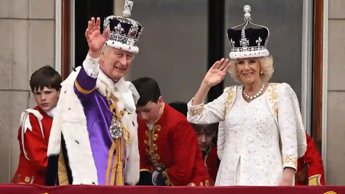 King Charles and Queen Camilla waving on the balcony of the palace after their coronation