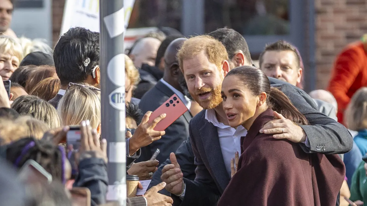 Prince Harry puts his arm protectively around Meghan.