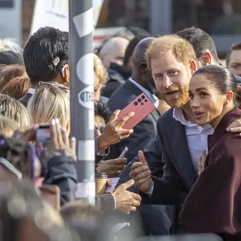 Prince Harry puts his arm protectively around Meghan.