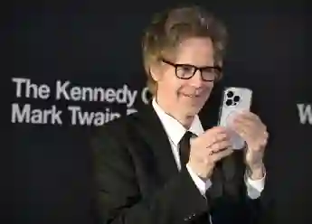 Comedian Dana Carvey uses his phone to take pictures of the photographers as he arrives on the red carpet for the 2023 K