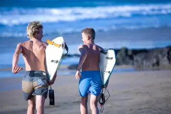 IMAGO Creative, Jahreszeit Sommer, Sommerferien Two teenage male surfers running toward sea, Fuerteventura, Spain, 29.04