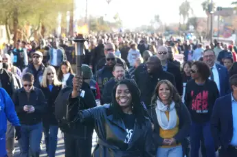 Syndication: Arizona Republic Rep. Quanta Crews carries a torch while joining hundreds of people marching through the st