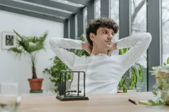 Contemplative businessman sitting with Newton s cradle at desk in office model released, Symbolfoto property released, Y