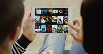 New York - Dec 01, 2017: Over shoulder view on the man and woman scrolling on the Netflix website on the tablet device a