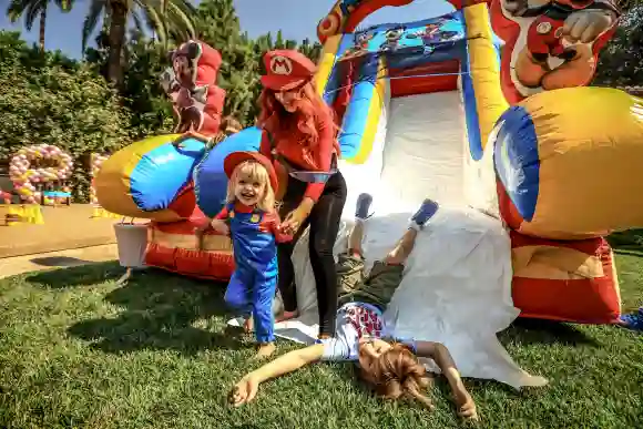 Singer Christina Aguilera, her daughter Summer Rain Rutler, and son Max Liron Bratman smile and laugh as they slide down the play slide during the second birthday party for Christina Aguilera's daughter.