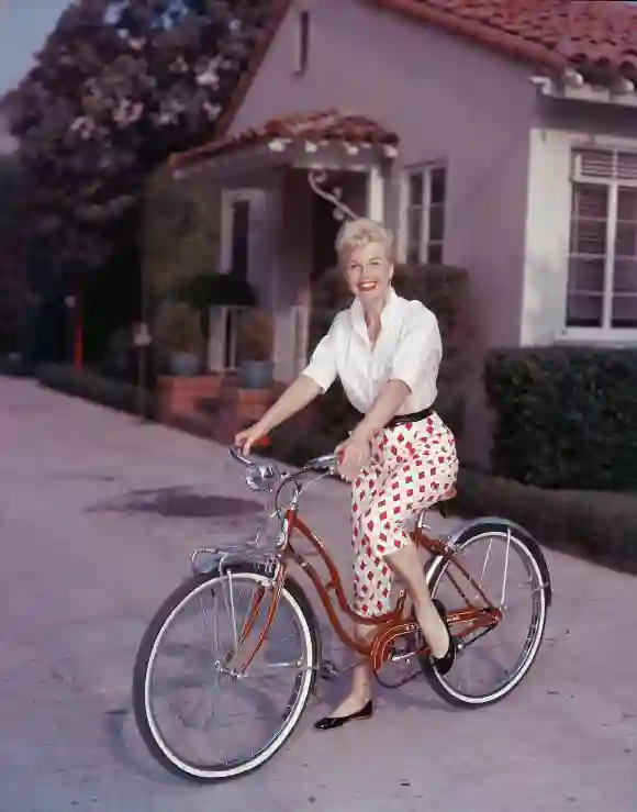 American actor Doris Day poses on a red Schwinn bicycle, late 1950s.