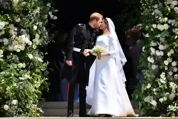 WINDSOR, UNITED KINGDOM - MAY 19: Britain's Prince Harry, Duke of Sussex kisses his wife Meghan, Duchess of Sussex as they leave from the West Door of St George's Chapel, Windsor Castle, in Windsor on May 19, 2018 in Windsor, England. (Photo by Ben STANSALL - WPA Pool/Getty Images)