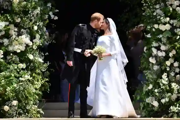 WINDSOR, UNITED KINGDOM - MAY 19: Britain's Prince Harry, Duke of Sussex kisses his wife Meghan, Duchess of Sussex as they leave from the West Door of St George's Chapel, Windsor Castle, in Windsor on May 19, 2018 in Windsor, England. (Photo by  Ben STANSALL - WPA Pool/Getty Images)