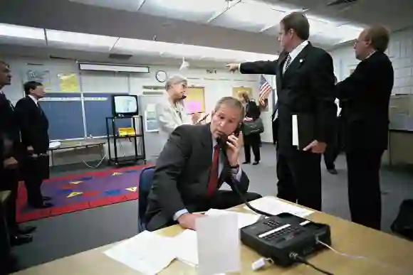 U.S President George W. Bush confers with staff via telephone as advisor Dan Bartlett points to news on the terror attacks in a secured classroom at Emma E. Booker Elementary School September 11, 2001