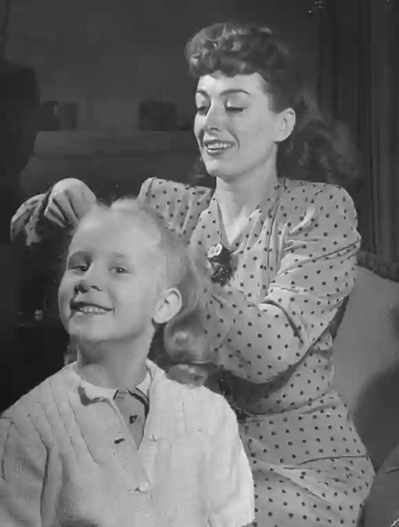 L'actrice Joan Crawford coiffe sa fille adoptive Christina Crawford, avec les 5-