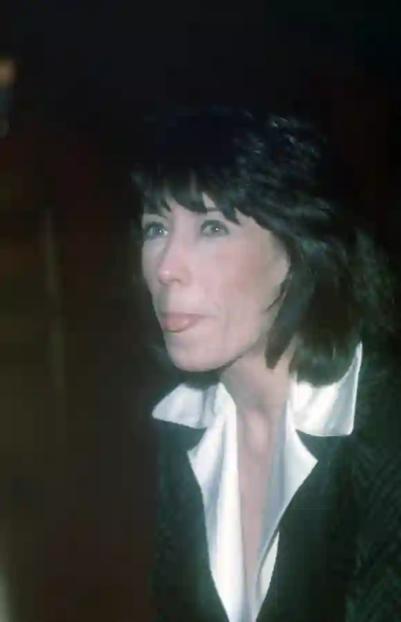 Lily Tomlin is an award winning comedian, actress, producer seen here in a side close-up, waering a black jacket and whi