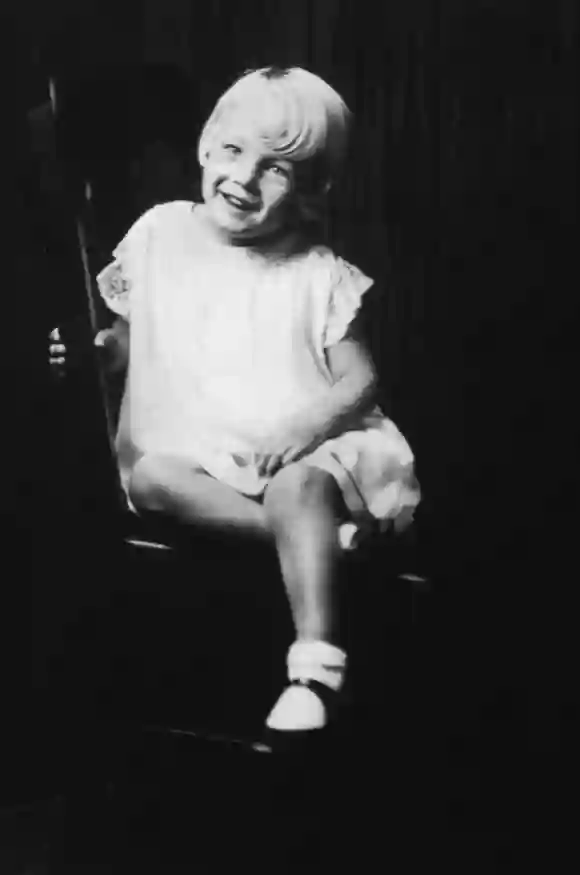 1931 : Portrait de l'actrice américaine Marilyn Monroe (1926-1962) à l'âge de 5 ans, assise sur une chaise en bois.
