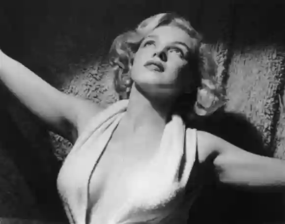 vers 1952 : Portrait de l'actrice américaine Marilyn Monroe (1926 - 1962) portant un dos nu décolleté sur un tapis.