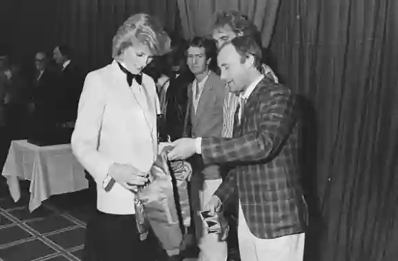 Diana, Princess of Wales (1961 - 1997) accepts a jacket with an embroidered gold crown for Prince William from British singer and drummer Phil Collins of rock band Genesis, before the band gave a Royal charity concert at the National Exhibition Centre, Birmingham, UK , 2nd March 1984. (Photo by Steve Wood/Daily Express/Hulton Archive/Getty Images)