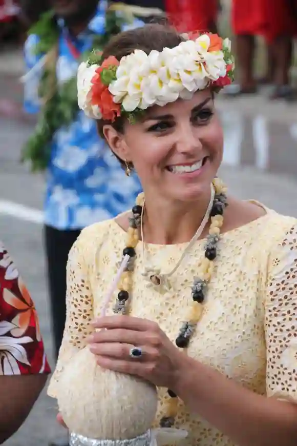 Duchess of Cambridge, wearing traditional headwear, drinks a coconut from a tree planted by Queen Elizabeth II during her 1982 tour, following Kate's arrival with husband Prince William in Funafuti in Tuvalu on September 18, 2012