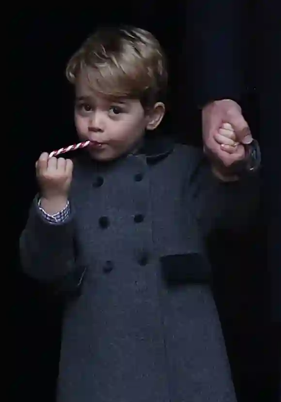 Prince George of Cambridge eats a sweet as he leave following the service at St Mark's Church on Christmas Day on December 25, 2016