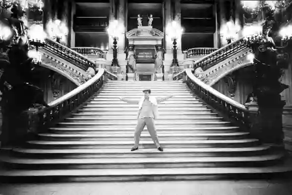 Actor  Gene  Kelly  dancing  on  the  steps  of  the  grand  staircase  (escalier)  of  the  Opera,