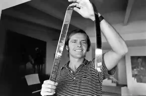 American  film  actor  Jack  Nicholson  grims  as  he  holds  up  a  strip  of  film  negative  in