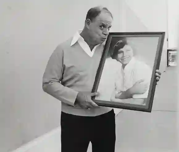 American  comedian  Don  Rickles,  holds  and  kisses  a  framed  picture  of  his  wife,  as  a  yo