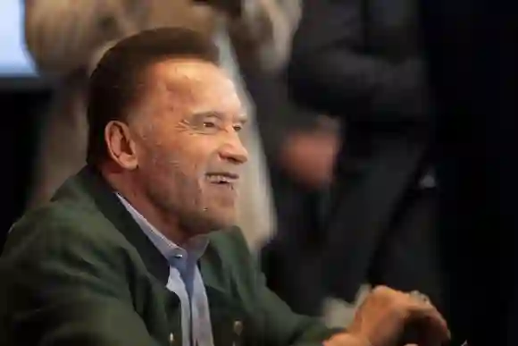 ARNOLD SCHWARZENEGGER laughing while signing copies of his book BE USEFUL: SEVEN TOOLS FOR LIFE at the AUSTRIAN WORLD SU