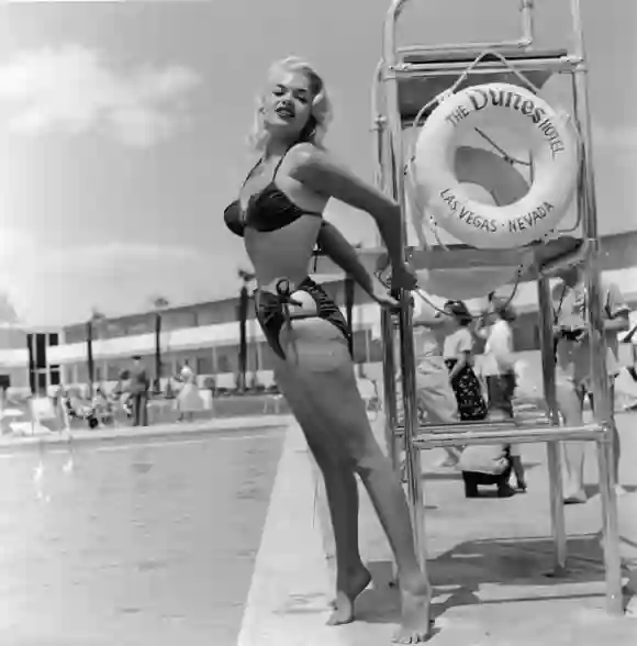 American film actor and sex symbol Jayne Mansfield (1933 - 1967) poses in a bikini by a lifeguard chair at the Dunes Hotel, Las Vegas, Nevada, mid 1950's