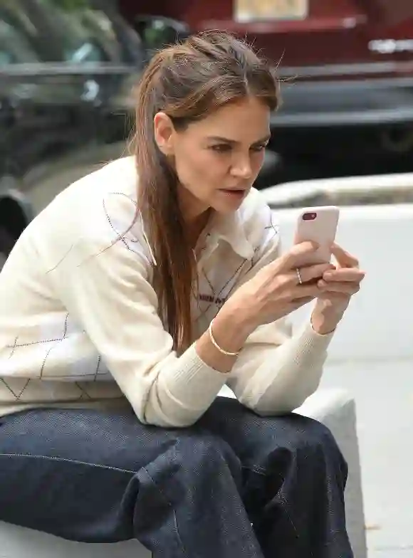 Katie Holmes on her phone outside an office not he upper west side in jeans, argyle sweater and Tacori crescent eclipse