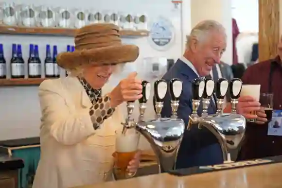 Prince Charles, Prince of Wales and Camilla, Duchess of Cornwall pull pints as they visit Quidi Vidi Brewery during their tour of Quidi Vidi Village, May 17, 2022.
