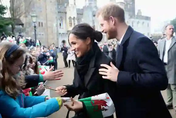 Meghan Markle writes a note for 10 year old Caitlin Clarke from Marlborough Primary School as Prince Harry looks on during a walkabout at Cardiff Castle, January 18, 2018.