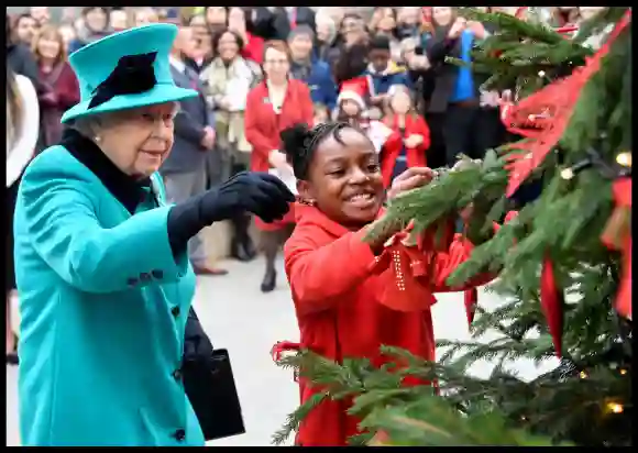 Queen Elizabeth and Shylah Gordon, aged 8, attach a bauble to a Christmas tree in London, Britain, on December 5, 2018.