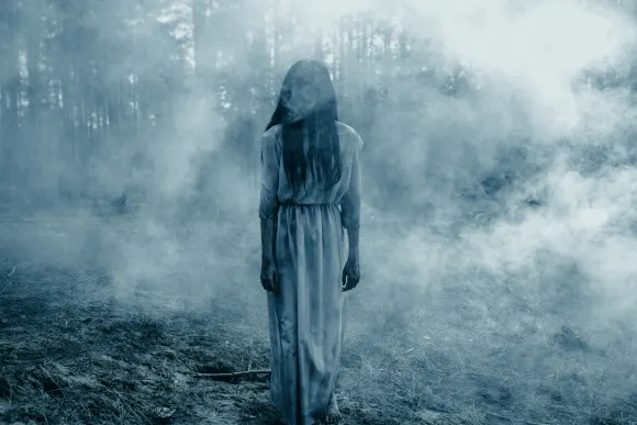 Girl with long black hair in image of scary ghost zombie walks among dark forest against background