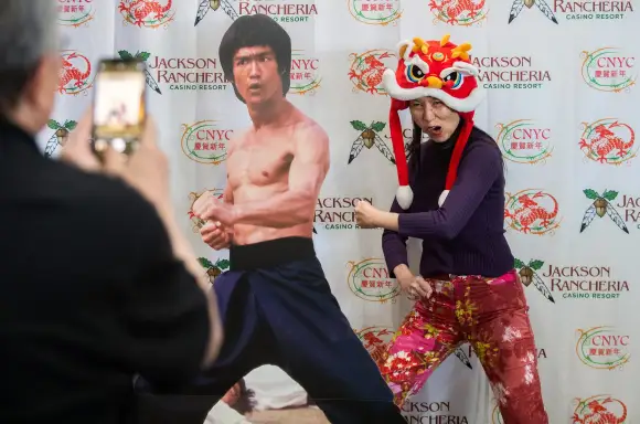 Syndication: Stockton Record Robin Kim has her picture taken by Wiilie Lao next to a cutout of martial arts legend Bruce
