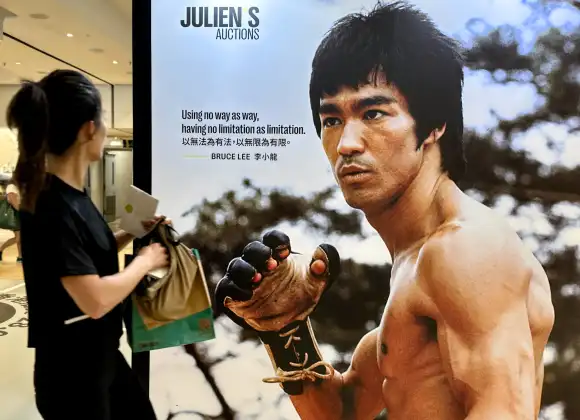 HONG KONG, CHINA - SEPTEMBER 14: A visitor walks by a poster of Bruce Lee during the Julien s Auctions Legends in Motion