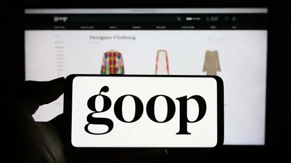 Person holding cellphone with logo of US publishing and e-commerce company Goop Inc. on screen. Stuttgart, Germany - 06-